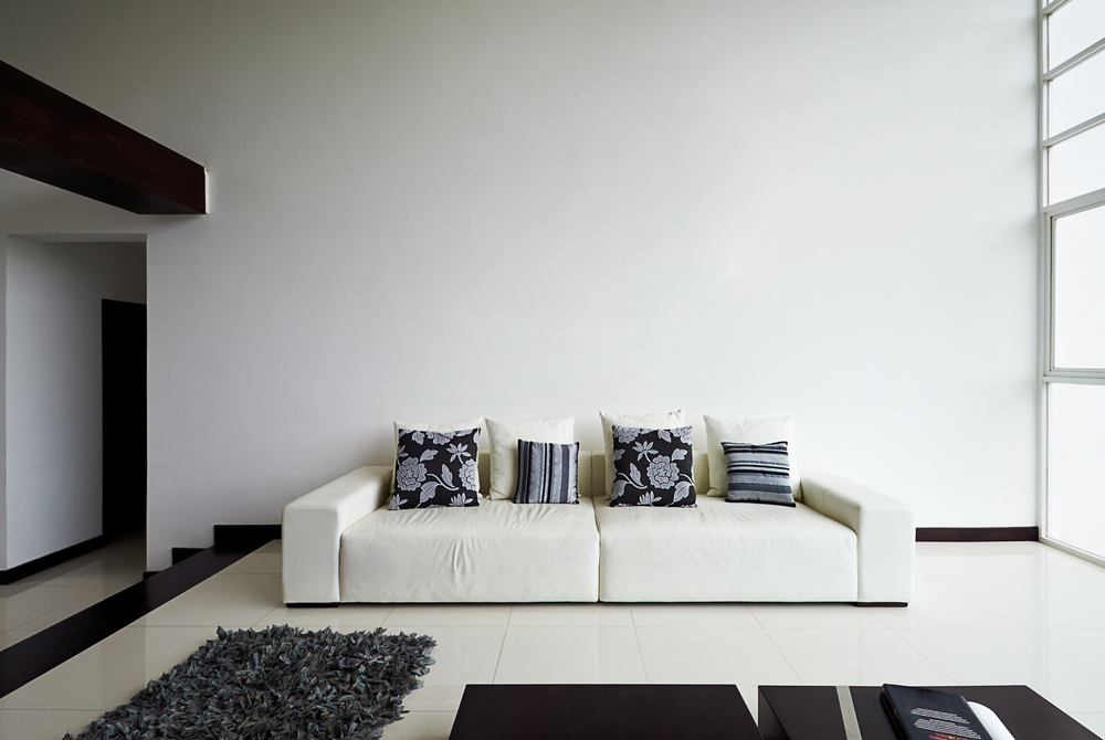 white couch in white room with black pillows and black rug