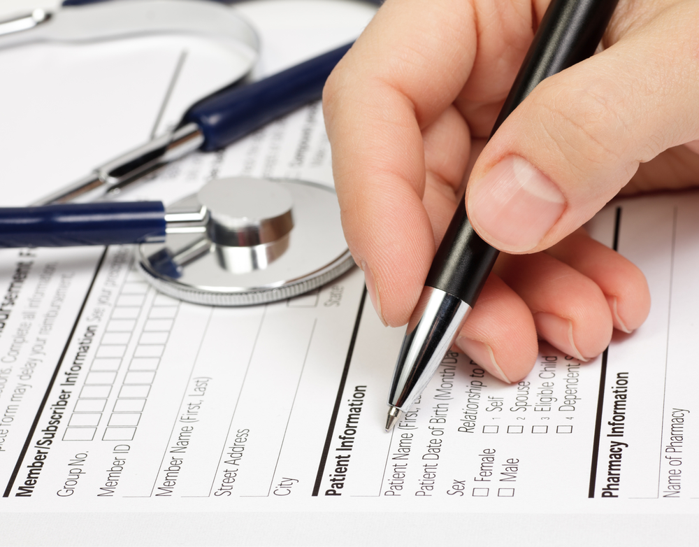 man filling out patient intake questions on paper