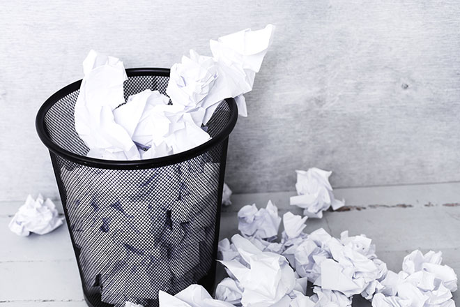 garbage can overflowing with crumpled papers