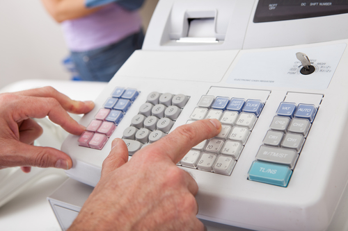 hand pressing buttons on a cash register